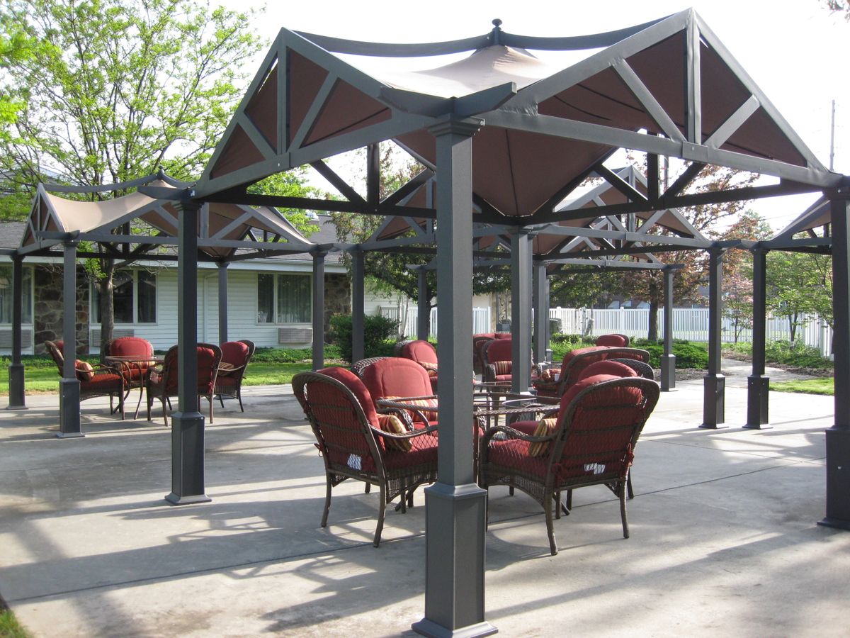 An outdoor patio area with tables and chairs under a gazebo.