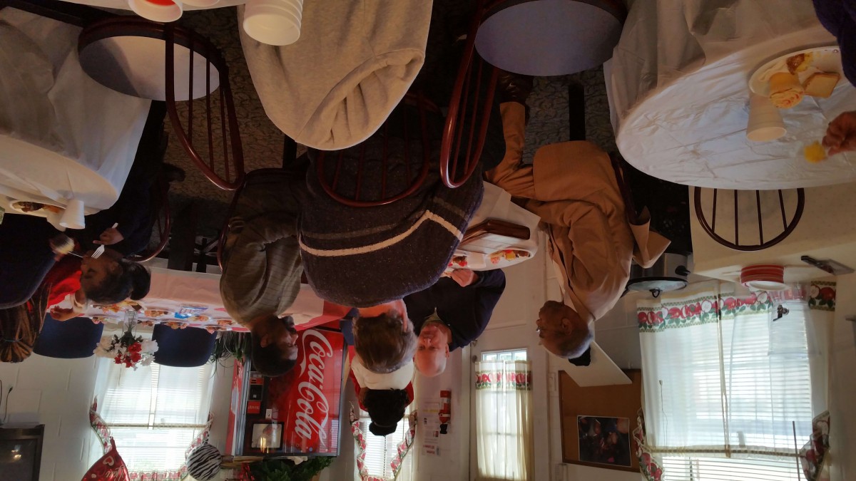 A group of people engaged in conversation inside a cozy cafe with a Coca-Cola sign on the wall.
