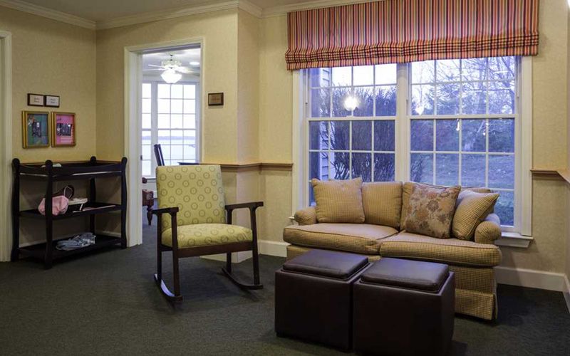 A cozy living room with a sofa, rocking chair, and large windows.