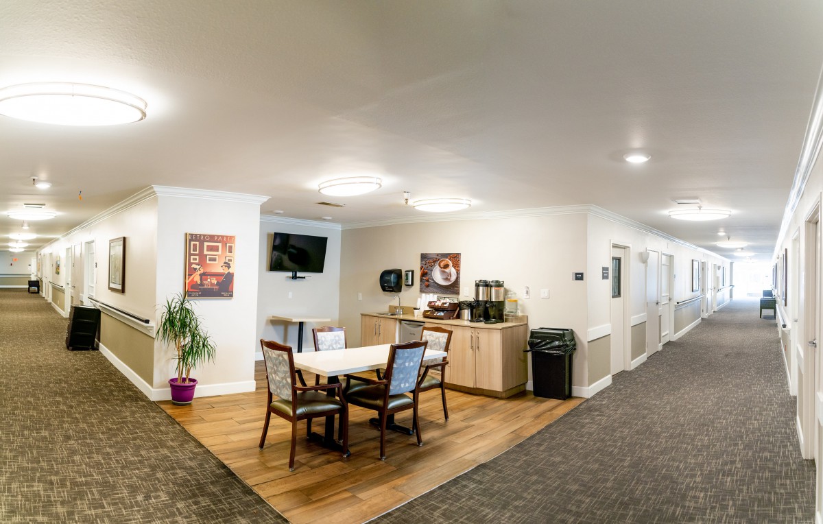 A cozy seating area in a hallway with a table, chairs, and a coffee station.