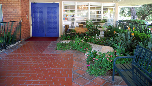 A welcoming garden entrance featuring vibrant blue doors and a beautifully landscaped path.