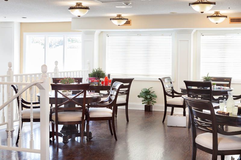 A well-lit dining area featuring stylish dark wood tables and chairs, with decorative plants adding a touch of greenery.