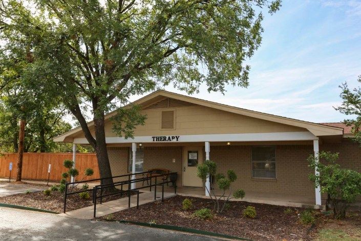 A small library building with a ramp and tree in front.