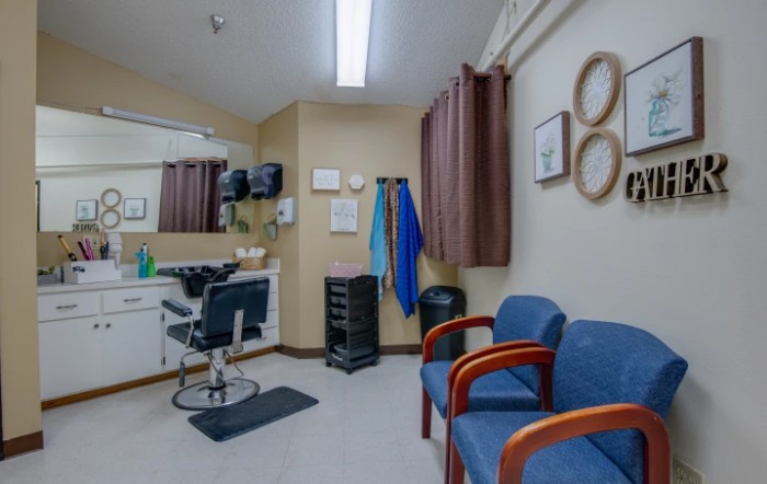 Interior view of a hair salon with styling chair, mirrors, and waiting area.