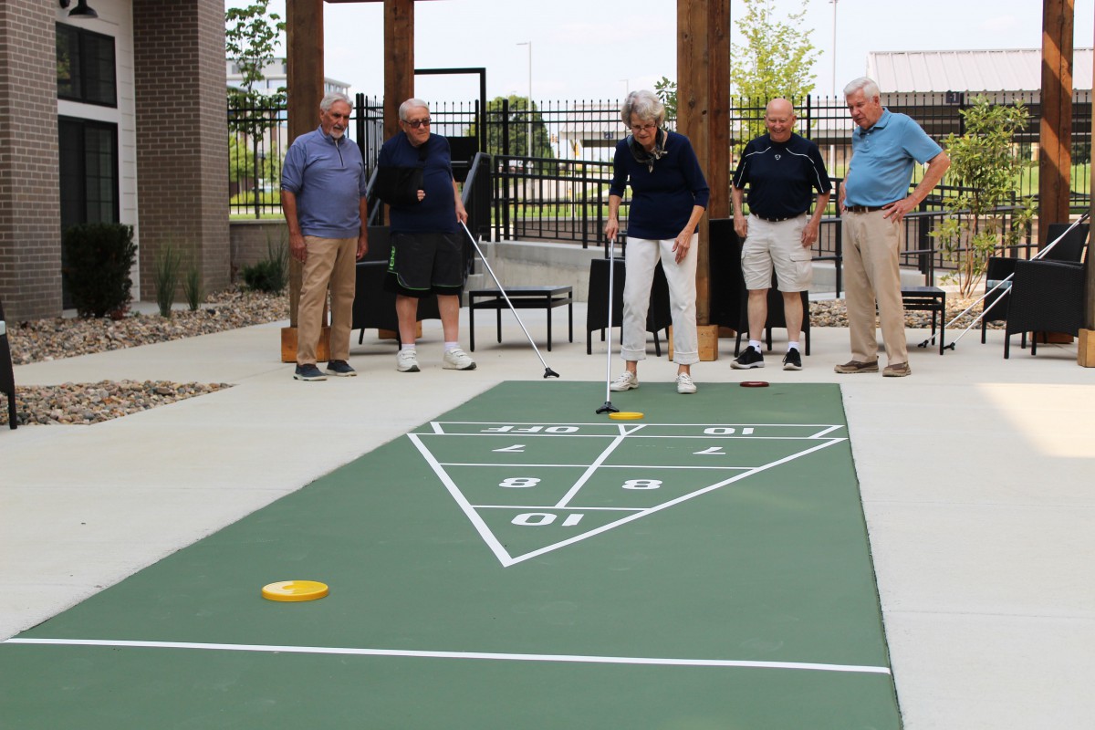 A group of seniors playing shuffleboard outdoors.