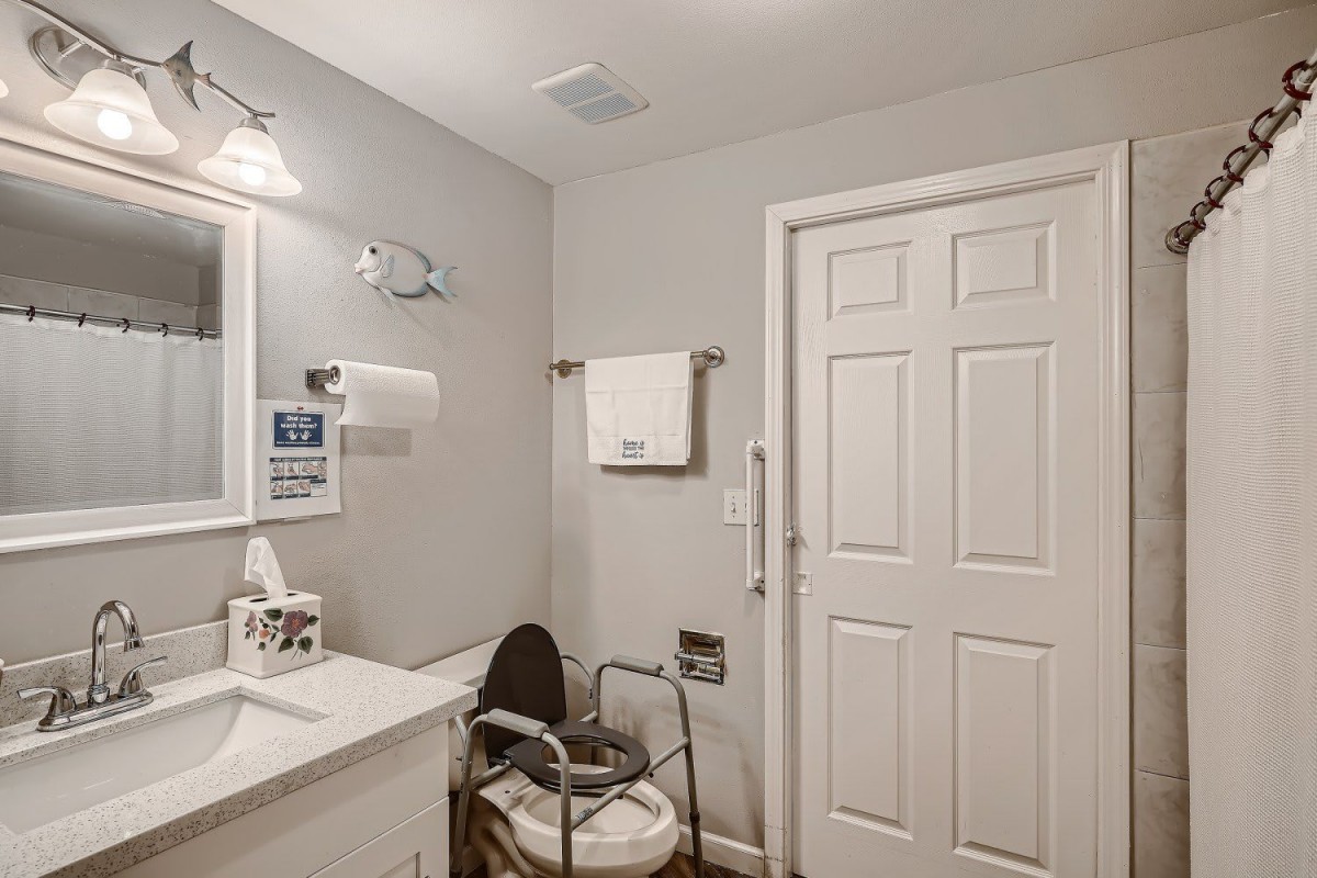 An accessible bathroom with a raised toilet seat, sink, and towel rack.