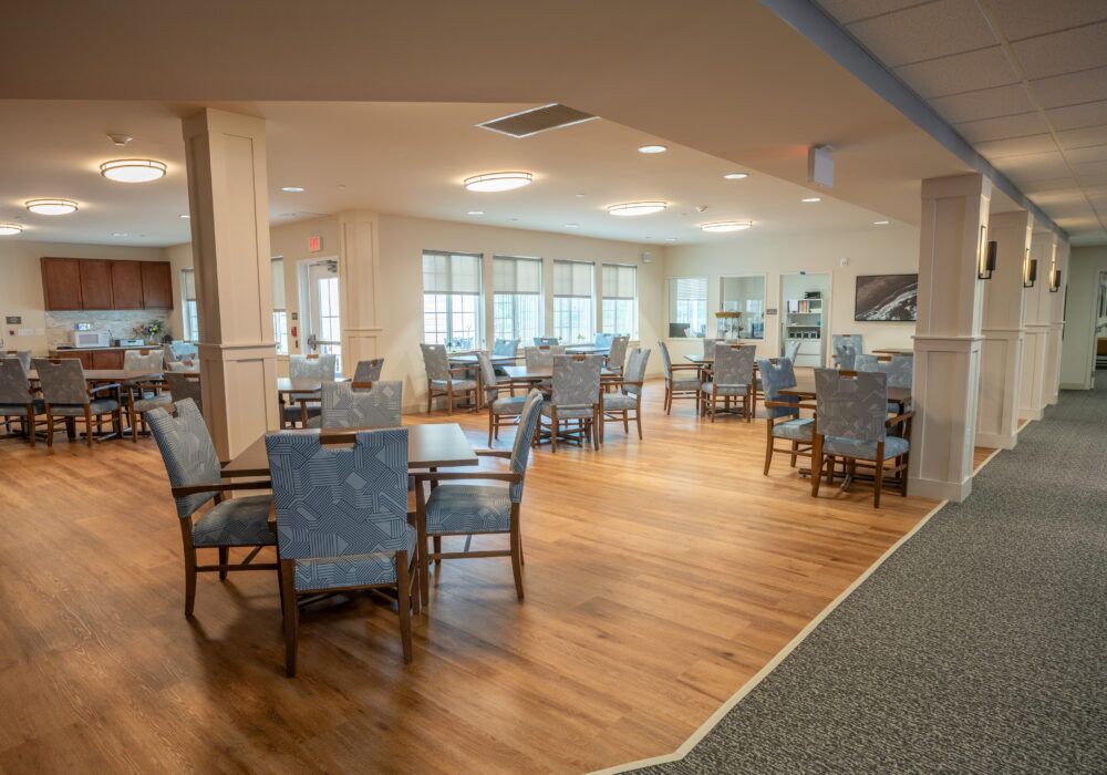 A spacious and well-lit dining area with several tables and chairs arranged neatly on a wooden floor.
