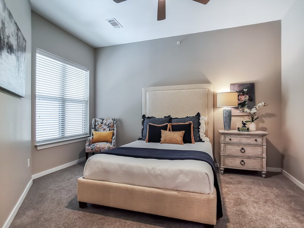 A modern and cozy bedroom with a neatly made bed, stylish armchair, and soft lighting.