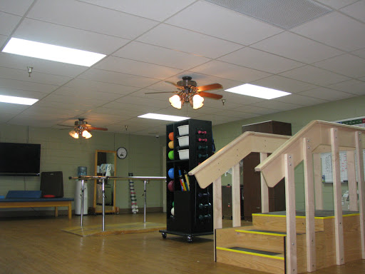 A spacious room featuring ceiling fans, a set of stairs, and various furniture arrangements.