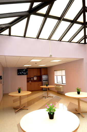 A modern office lounge area featuring tables, plants, and a television.