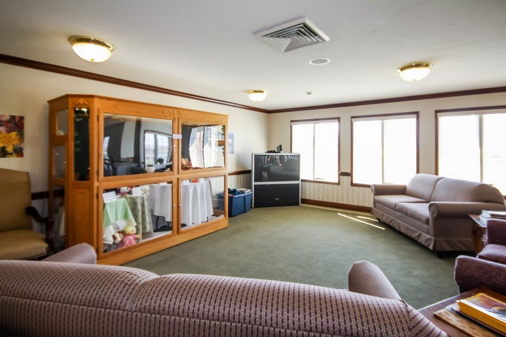 A cozy living room with a sofa, television, and large windows.