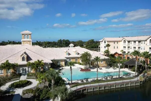 A luxurious resort featuring a large pool surrounded by palm trees and elegant architecture.