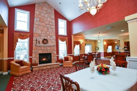 A cozy living room with a fireplace and adjacent dining area, featuring elegant furnishings and high ceilings.