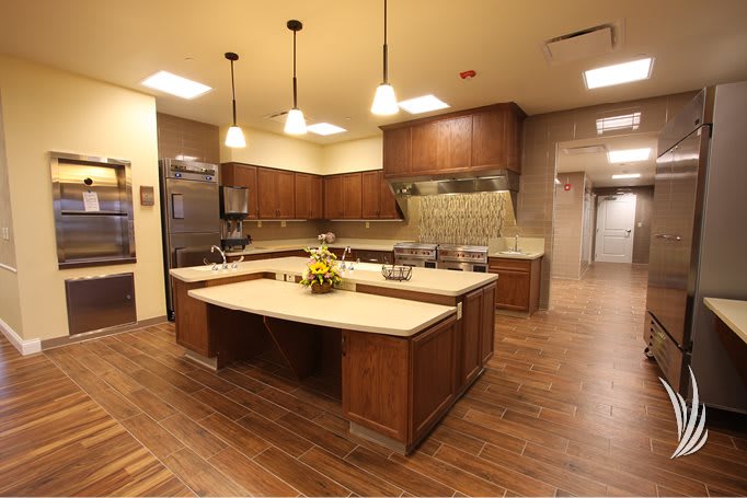 A modern kitchen with wooden cabinets, featuring a spacious island and stainless steel appliances.