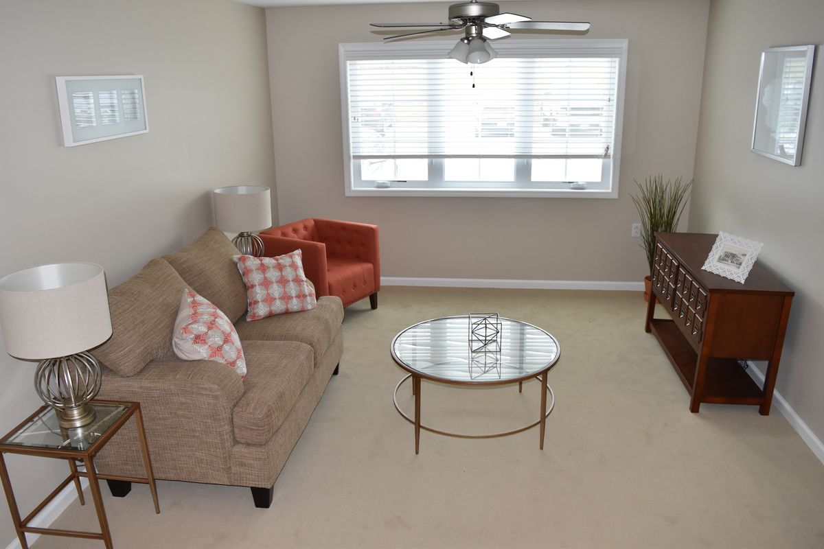 A cozy living room with a sofa, armchair, and coffee table under a ceiling fan.
