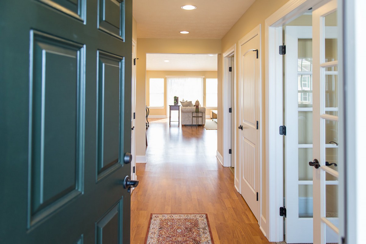A welcoming entryway with a view into a sunlit living area featuring wooden floors and neutral wall colors.