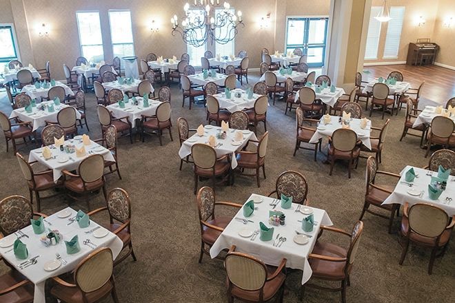 An elegantly arranged dining room with multiple tables and chairs set for a meal.