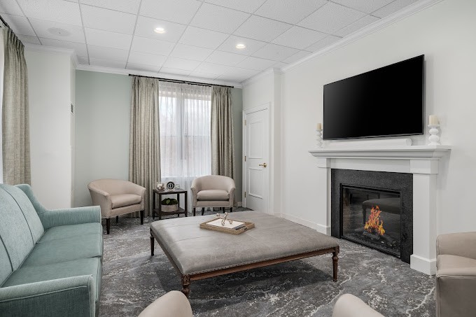 A modern living room with a cozy fireplace, television, and neutral-toned furniture.