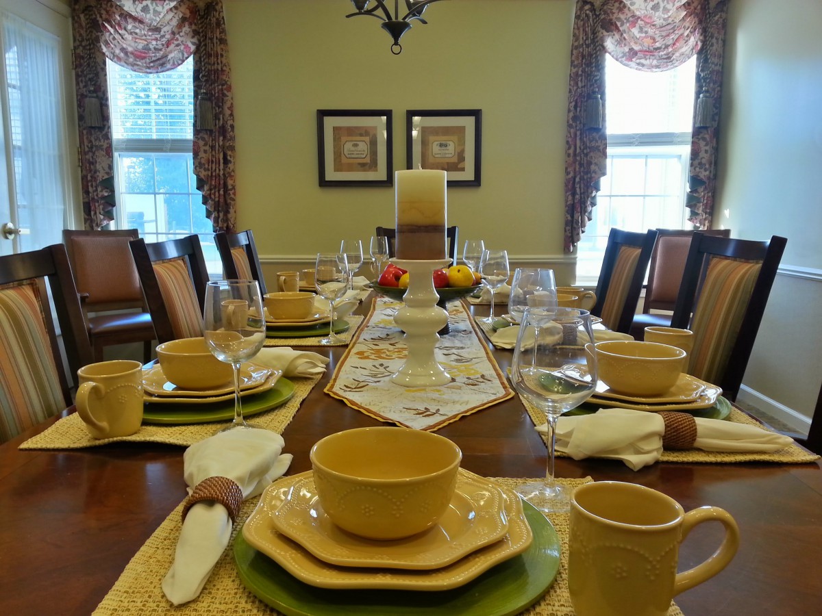 A beautifully set dining table with dinnerware and a decorative centerpiece.