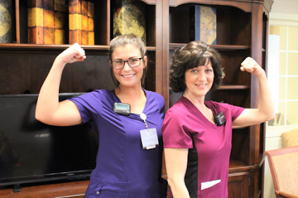Two nurses proudly flexing their arms and smiling.
