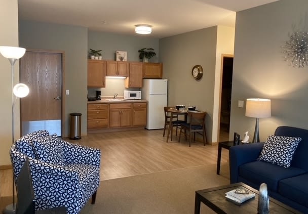 A cozy apartment interior with an open-plan living room and kitchen area, featuring comfortable furniture and warm lighting.