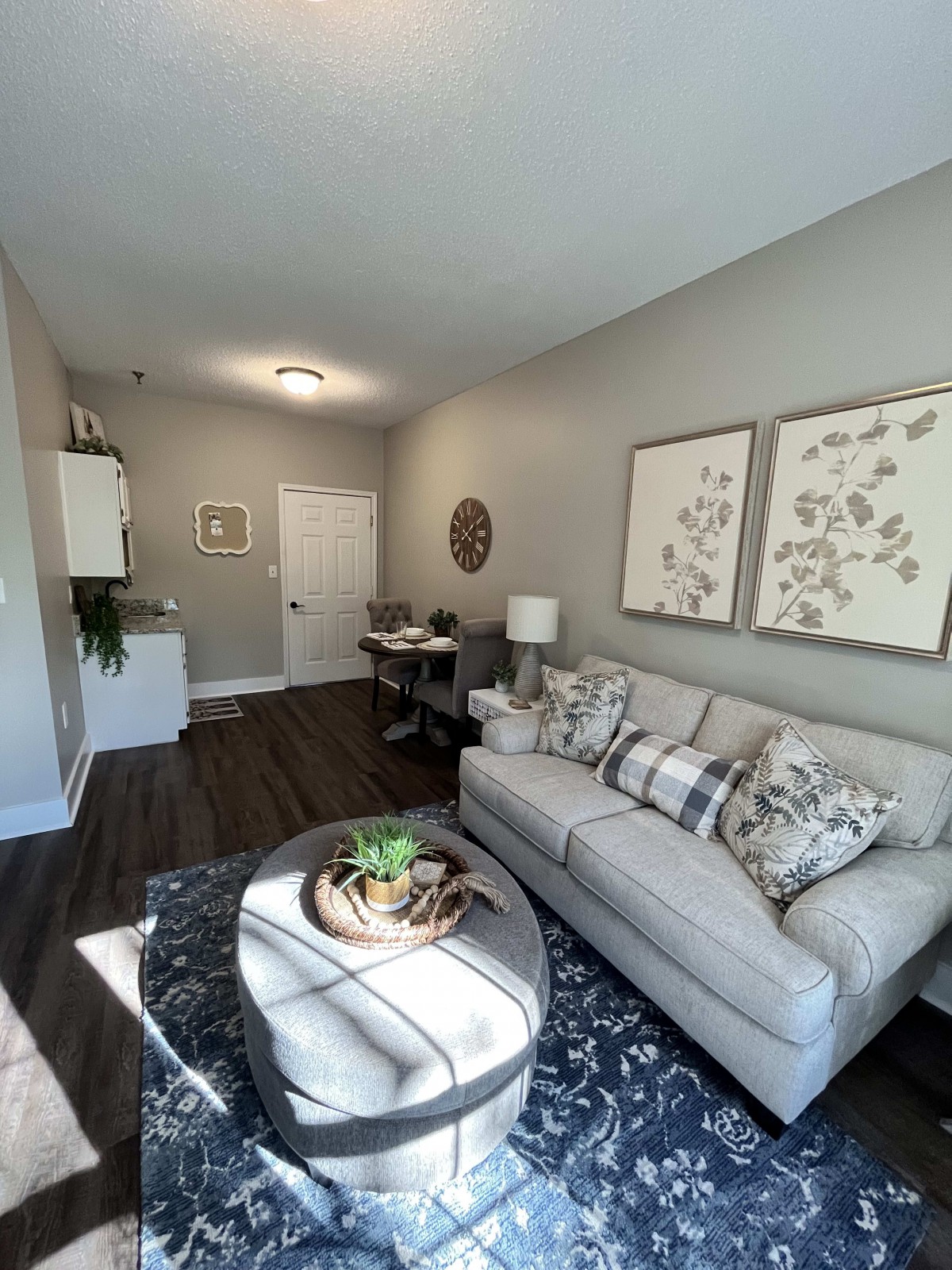 A modern living room with a comfortable sofa, decorative artwork, and a stylish coffee table on a dark hardwood floor.