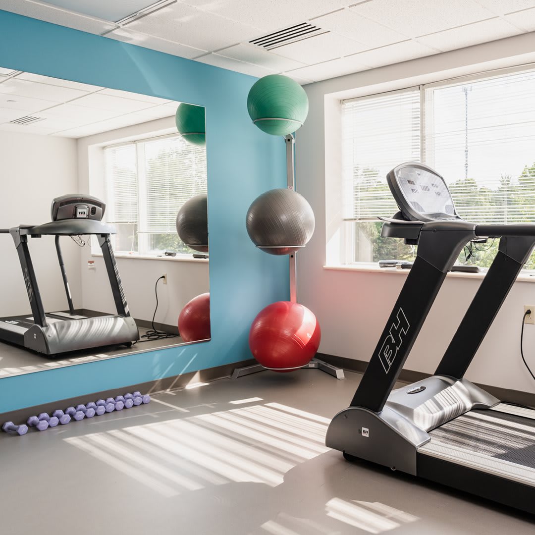 A well-lit gym room with treadmills, exercise balls, and yoga mats.