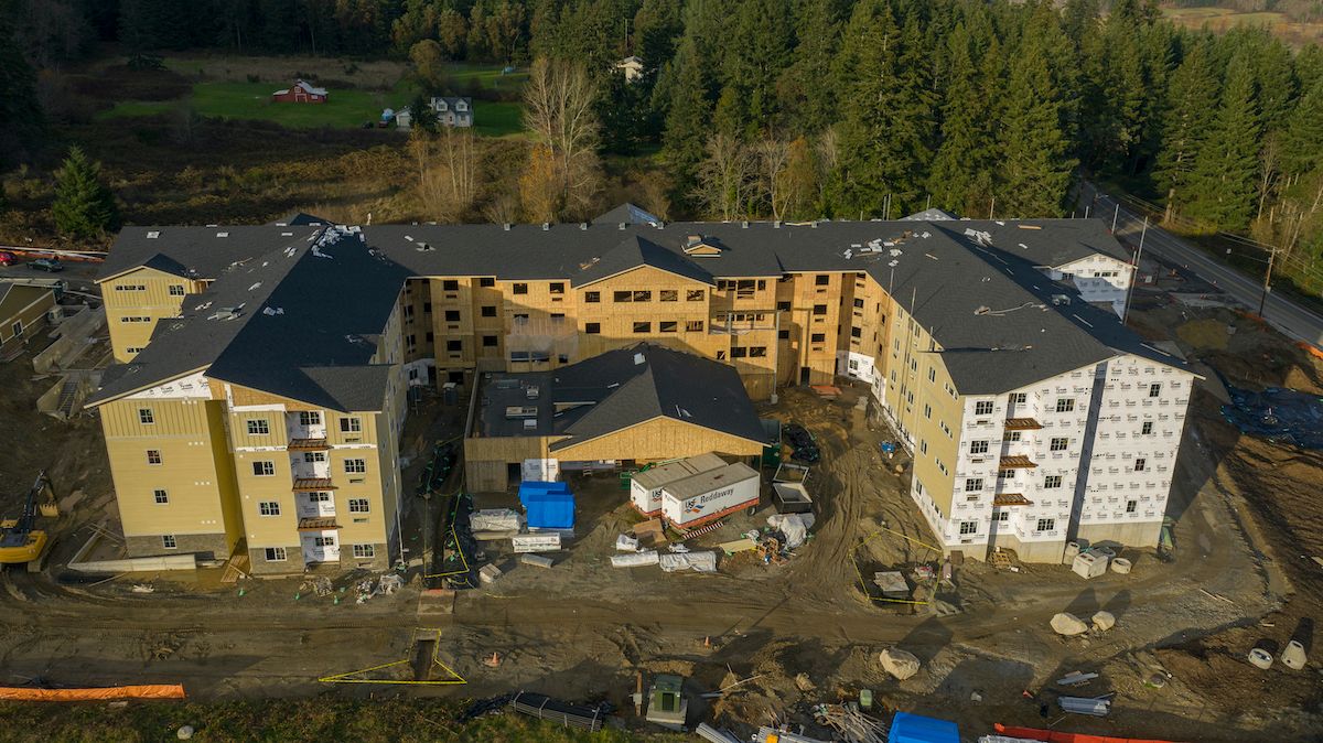 Aerial view of a residential building under construction surrounded by trees.
