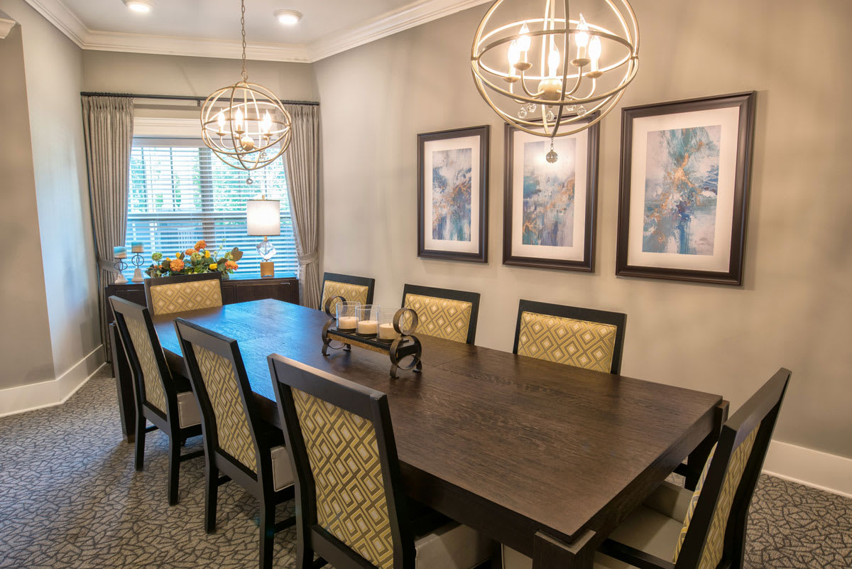 A stylish dining room with a large wooden table, elegant chairs, and decorative chandeliers.