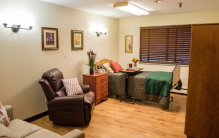 A cozy bedroom interior in a care facility with comfortable furniture and warm decor.