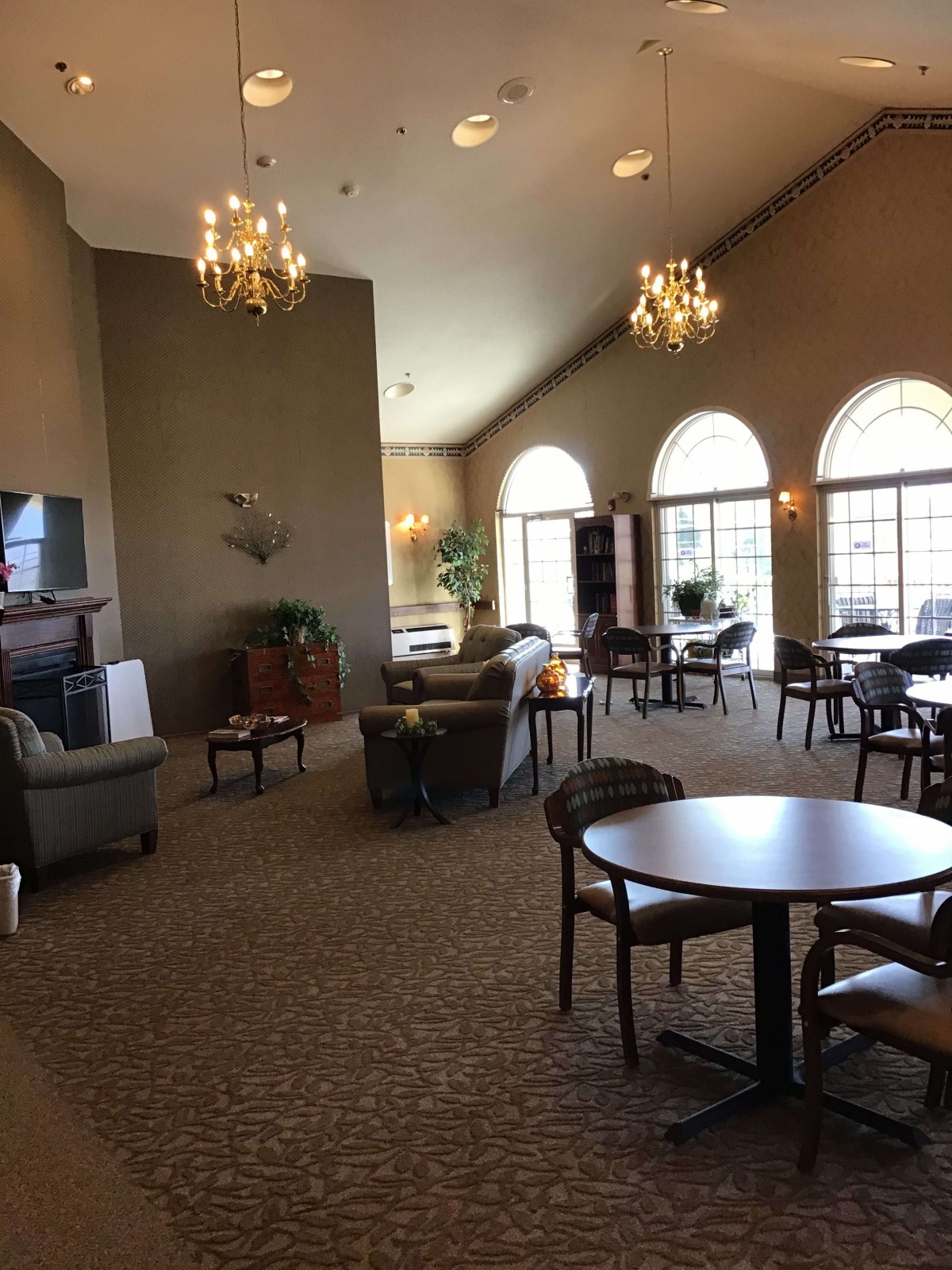 A spacious and elegant lounge area with comfortable seating, large windows, and chandeliers.