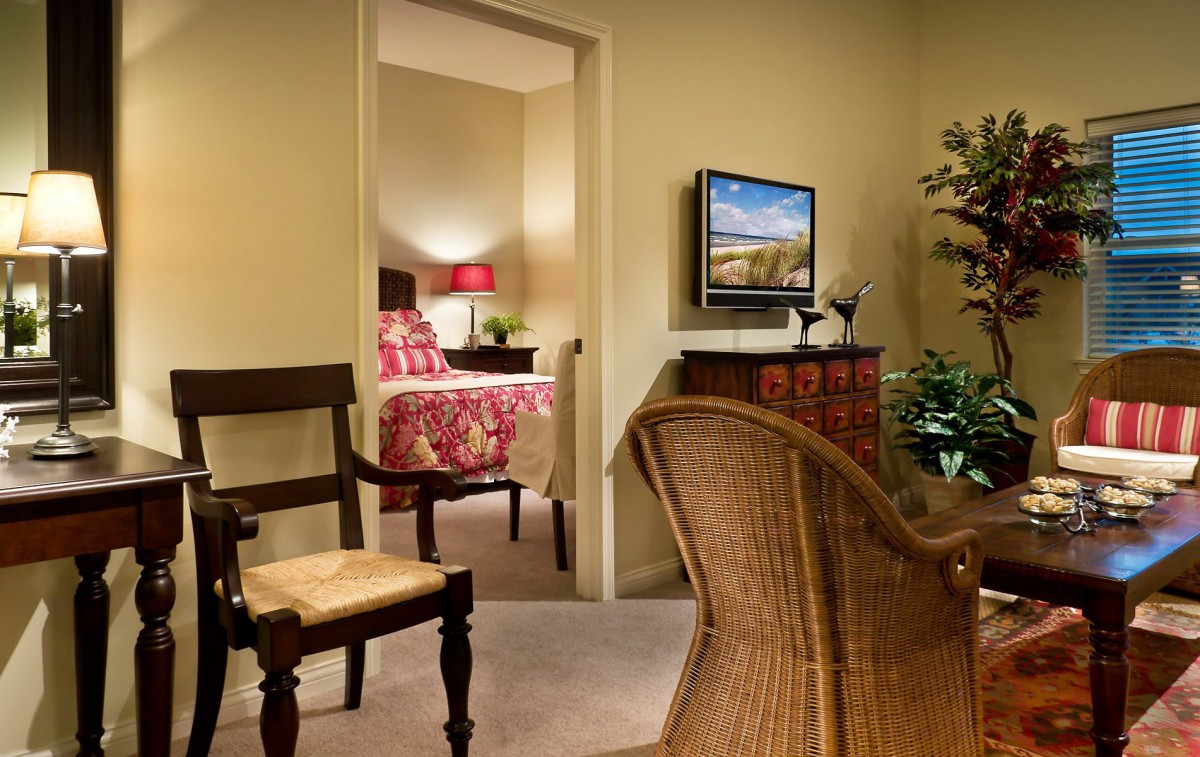 A cozy living area with a view into a well-decorated bedroom.