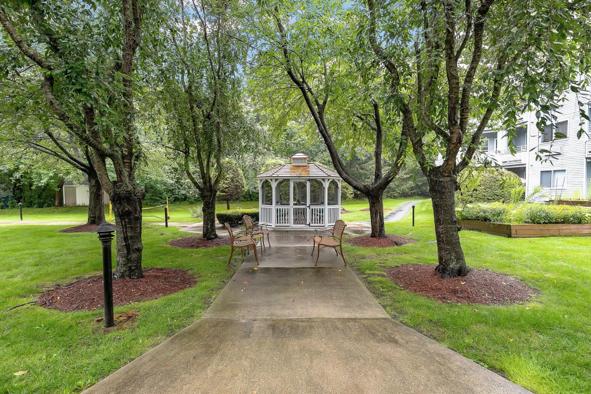 A serene garden path leads to a charming gazebo surrounded by lush trees.
