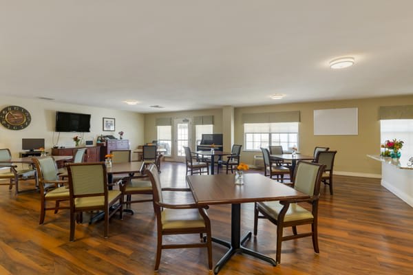 A spacious dining area with wooden floors, tables, and chairs.