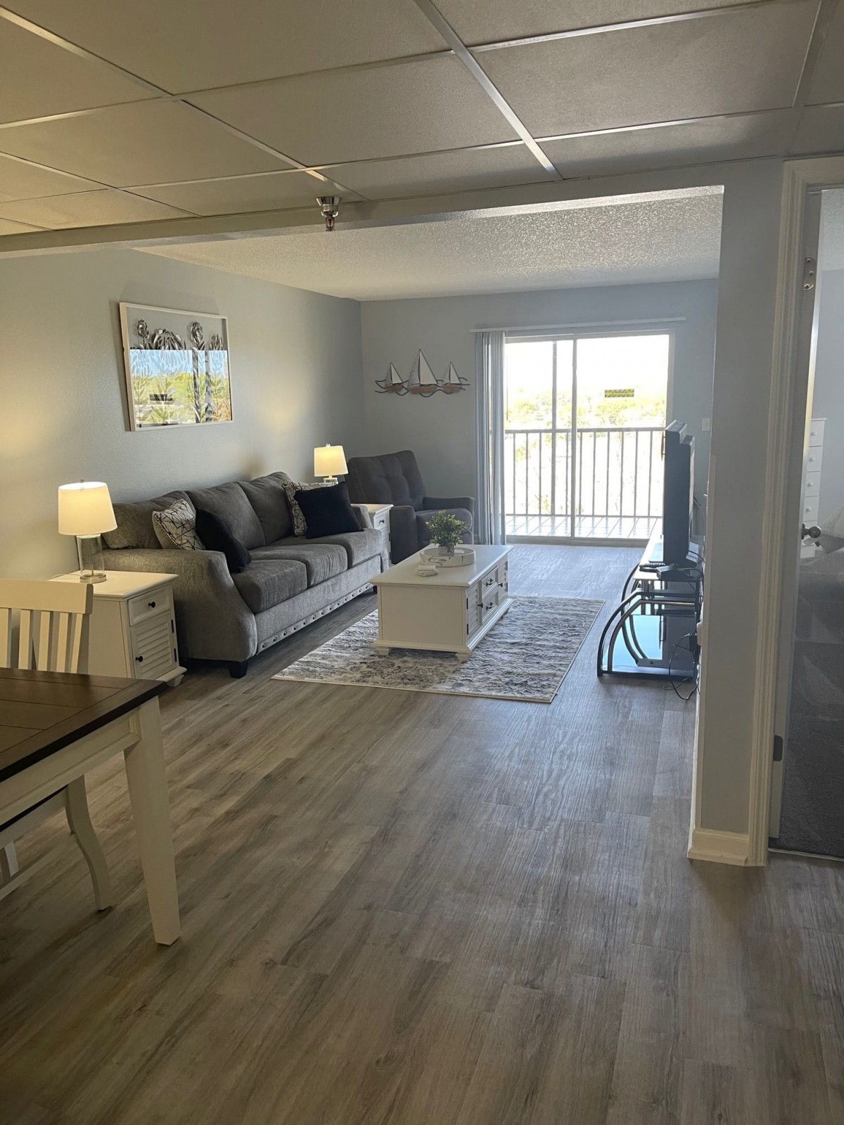 A modern living room with a comfortable couch, coffee table, and television, complemented by a dining area and tasteful decor.