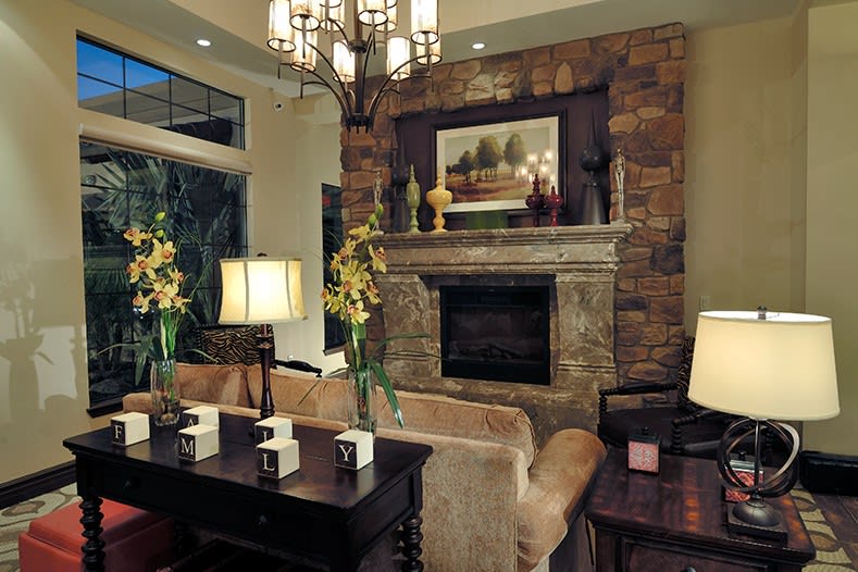 A cozy living room with a stone fireplace, elegant chandelier, and comfortable seating arrangement.