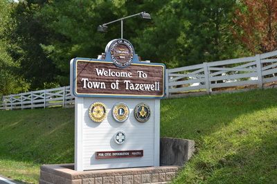 A welcome sign for the Town of Tazewell featuring various emblems and greenery in the background.