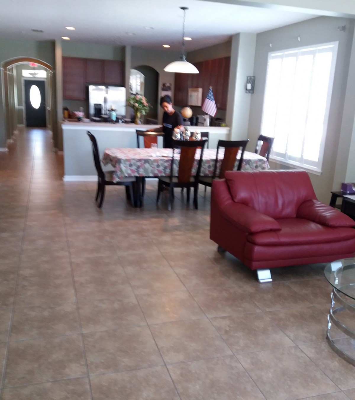 An open-concept living and dining area with a red chair and a kitchen in the background.
