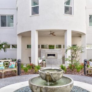 A modern courtyard with a central fountain, surrounded by outdoor seating and lush plants.