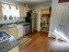 A modern kitchen featuring wooden floors, cream-colored cabinets, and stainless steel appliances.