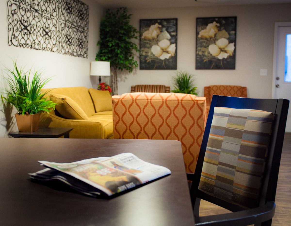 A cozy waiting room with comfortable seating, decorative plants, and artwork on the walls.