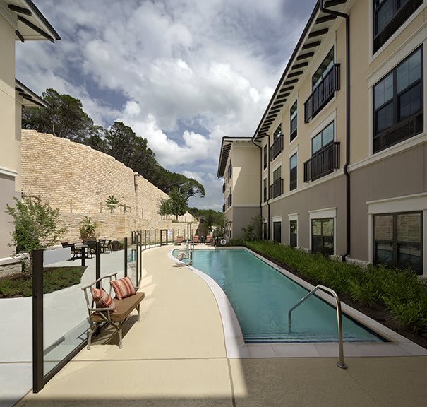 Modern apartment complex with an outdoor swimming pool surrounded by greenery.