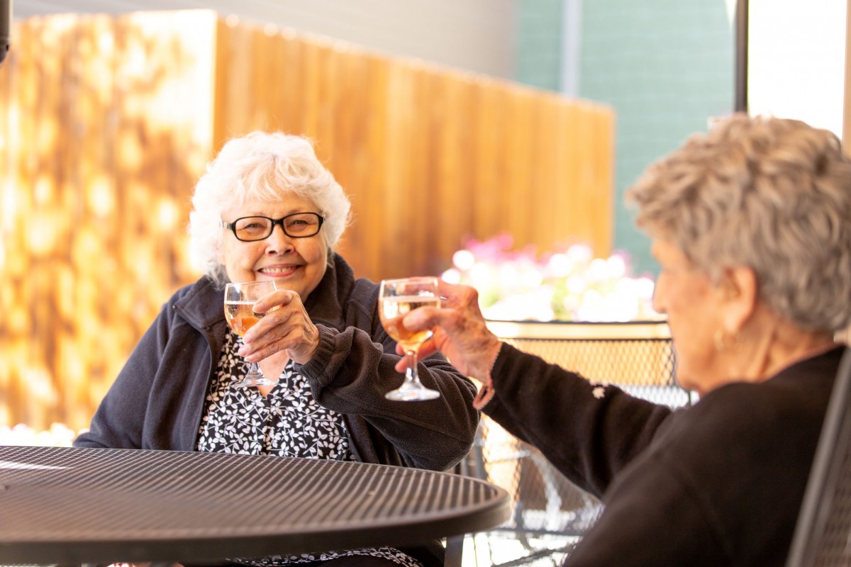 Two seniors enjoying a cheerful toast outside.