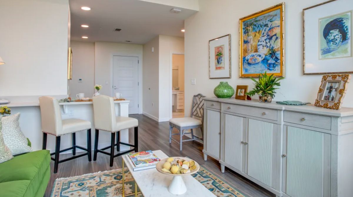 A modern living room with minimalist decor featuring a dining area and colorful artwork.