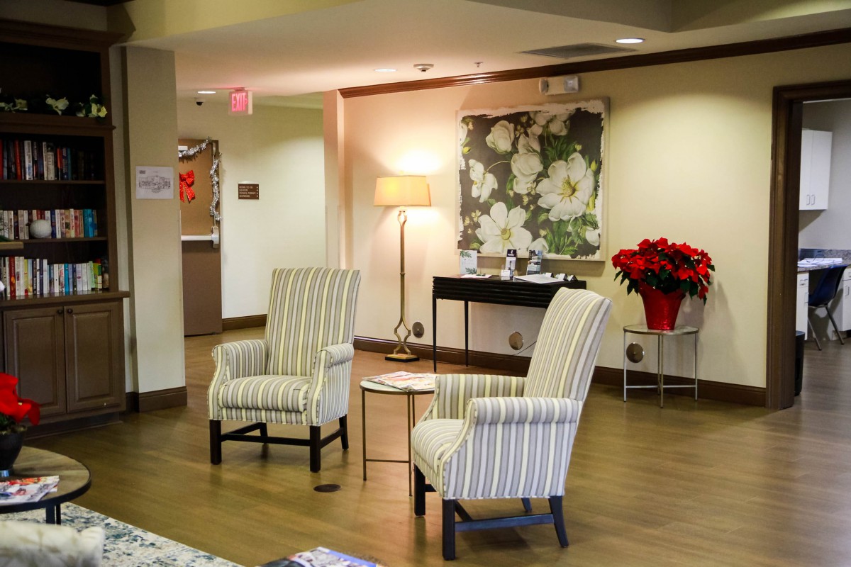 A cozy lobby area with striped chairs, a lamp, and floral decor.