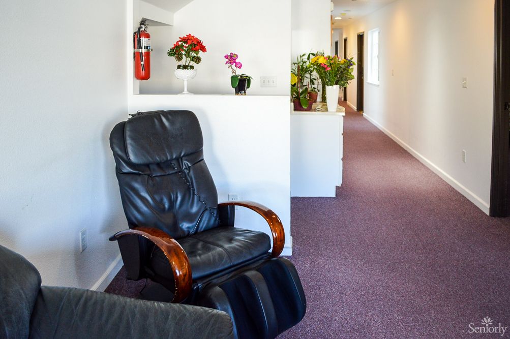 A quiet hallway featuring a comfortable leather chair and decorative plants.