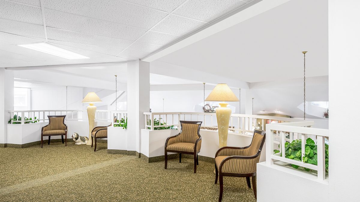 A modern lobby seating area with wicker chairs, large lamps, and a carpeted floor.