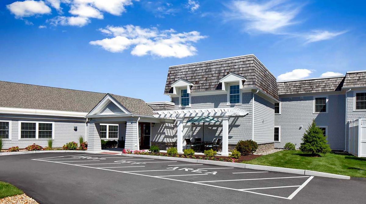 A hotel exterior with a parking lot and clear blue sky.