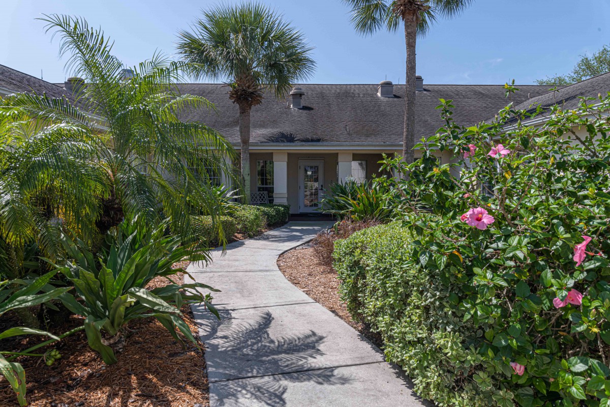 A charming house with a lush tropical garden and a curving pathway leading to the entrance.