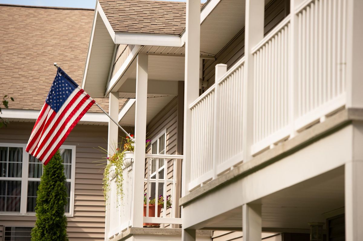 A residential house with an American flag displayed on the porch.